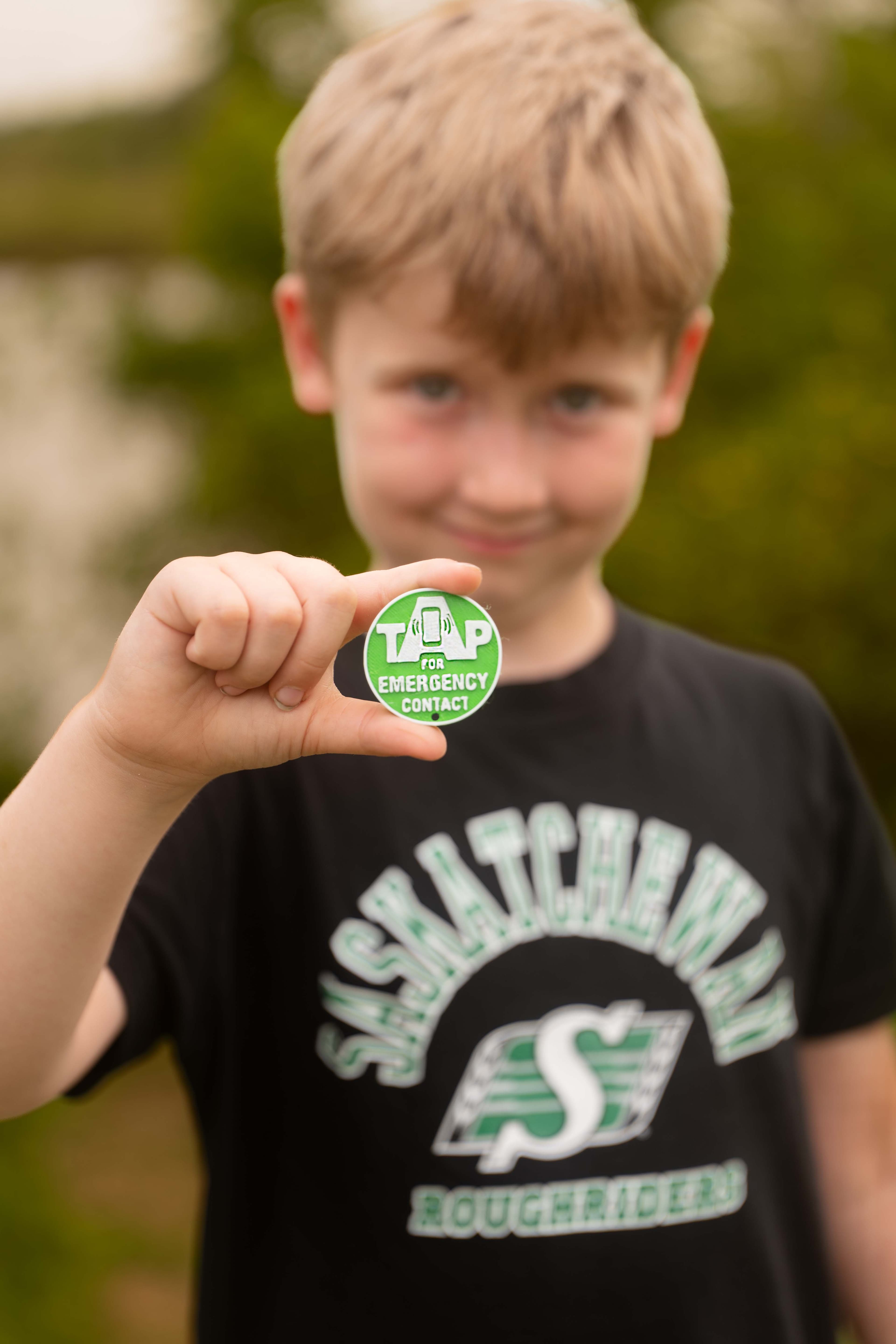 A boy wearing Roughriders gear holding his KinTag